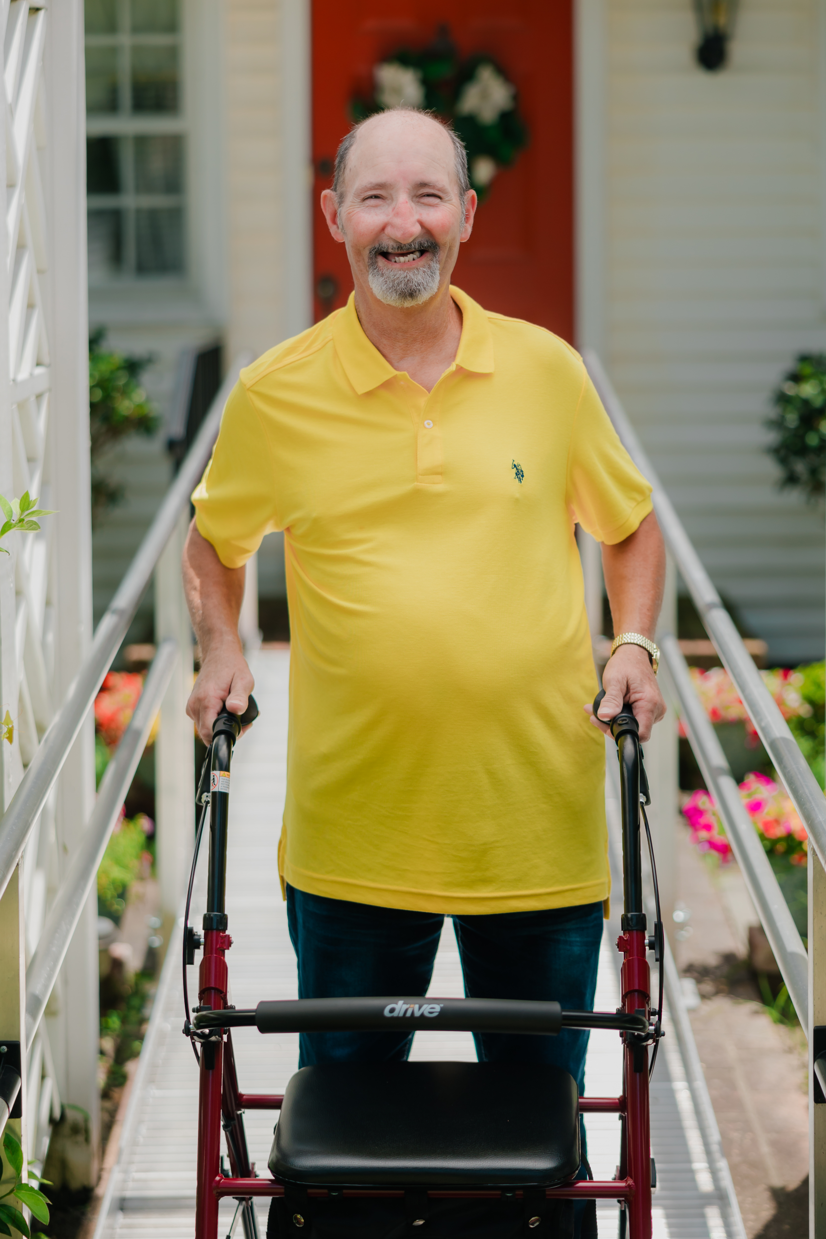 man in yellow shirt standing on an aluminum wheelchair ramp